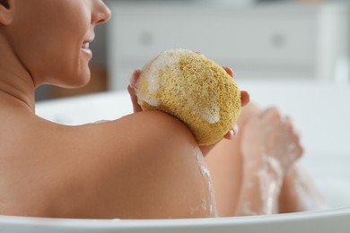 Woman with sponge taking bubble bath, closeup