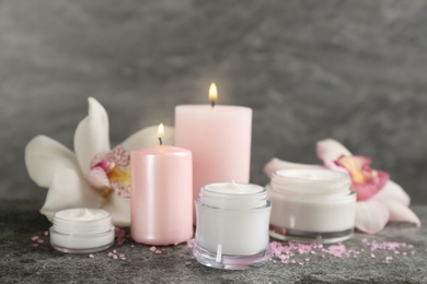 Photo of Beautiful spa composition with cosmetic products, candles and flowers on grey table