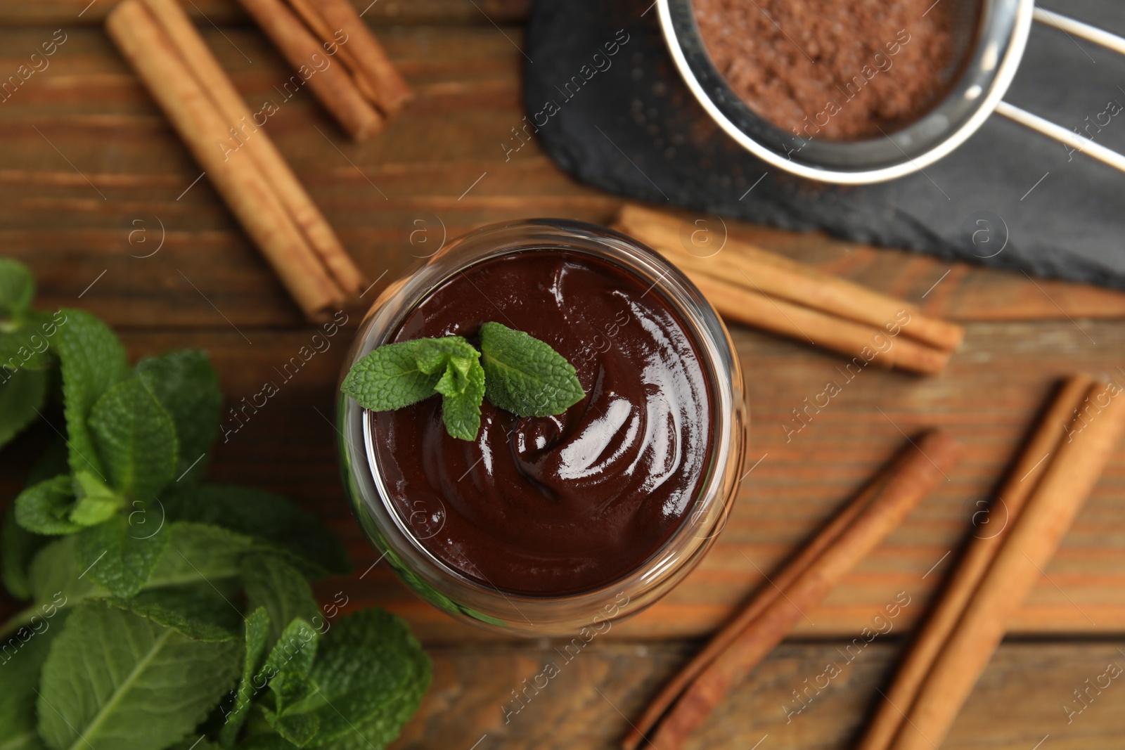 Photo of Glass of delicious hot chocolate with fresh mint and cinnamon sticks on wooden table, flat lay