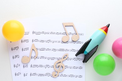 Photo of Wooden notes, music sheets and toys on white background, top view. Baby song concept
