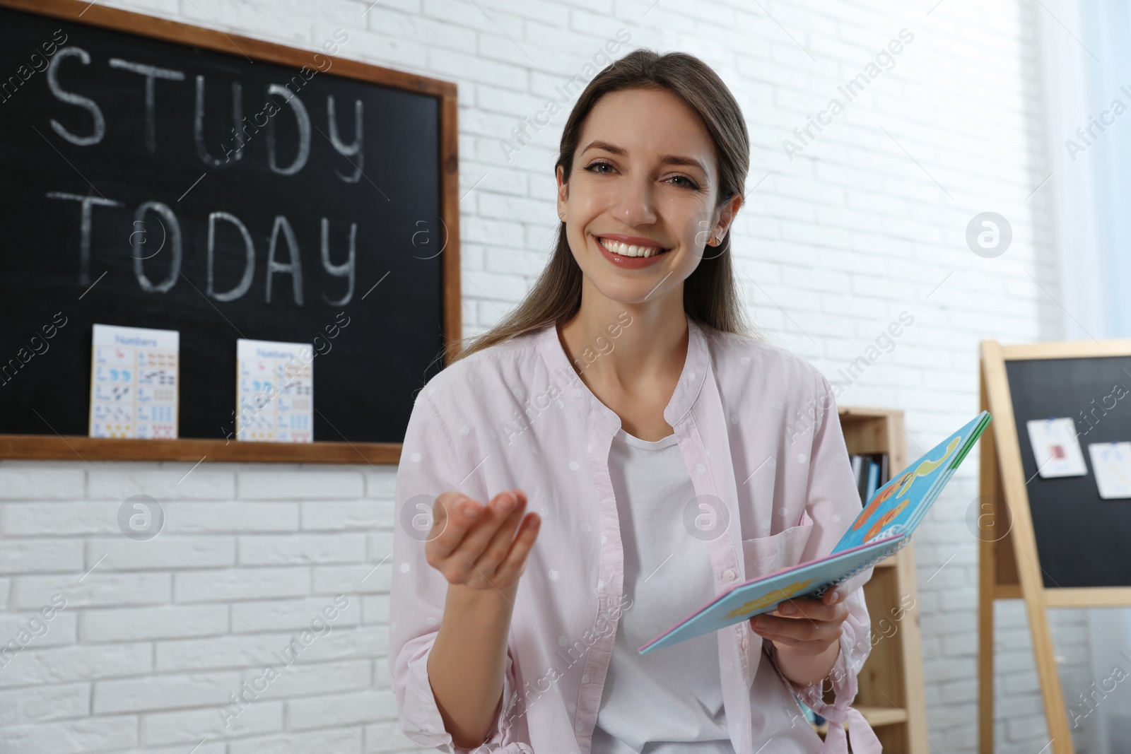 Photo of Happy female English teacher giving lesson in elementary school