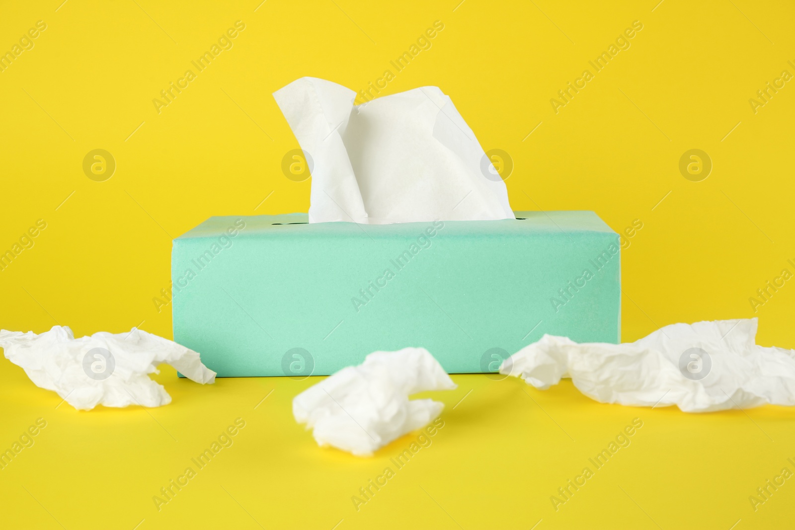 Photo of Used paper tissues and box on yellow background