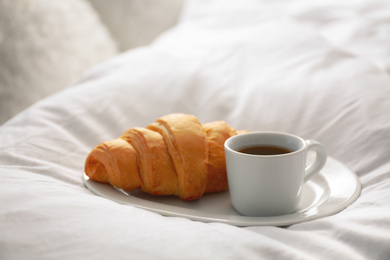 Photo of Delicious morning coffee and croissant on bed