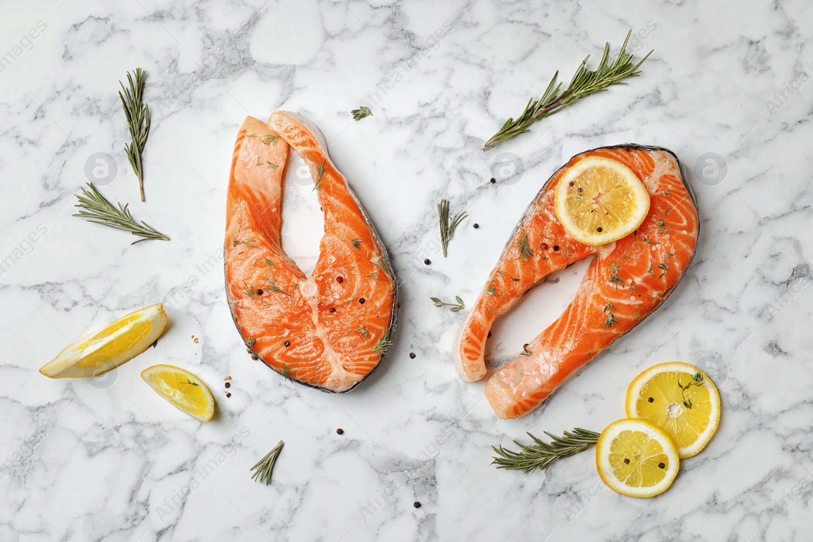 Photo of Fresh raw salmon steaks and seasonings on marble background, top view