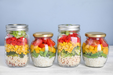 Photo of Glass jars with healthy meal on white wooden table