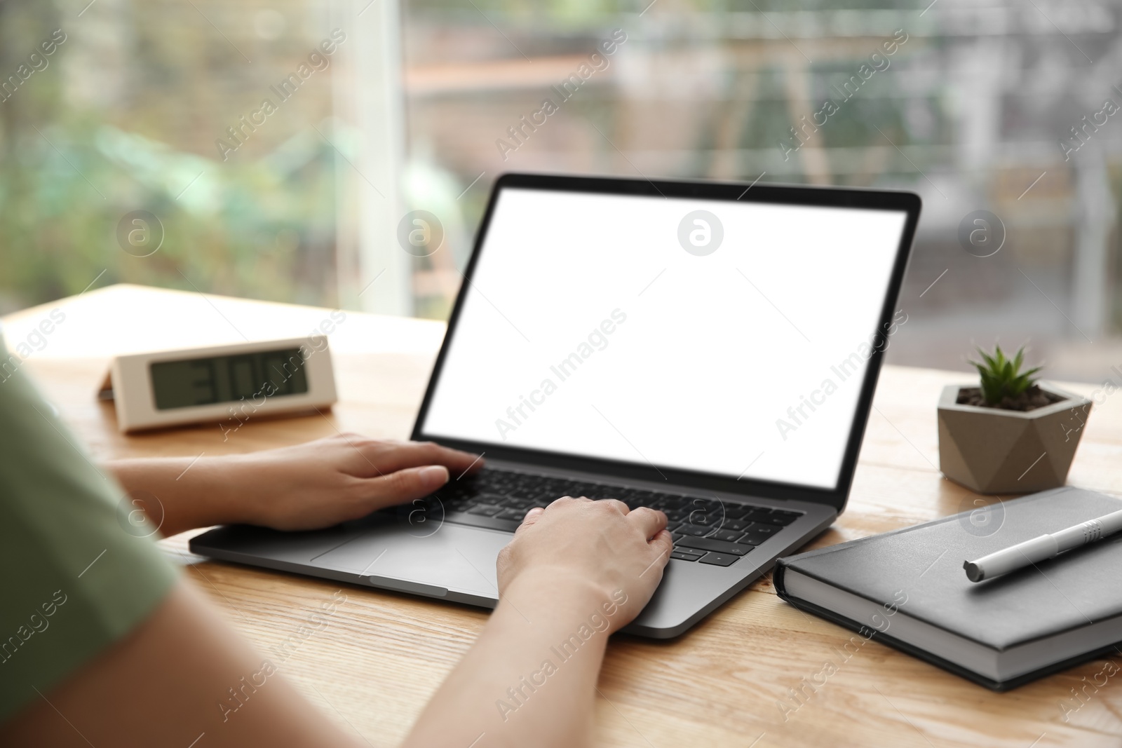 Photo of Woman working with modern laptop at wooden table, closeup