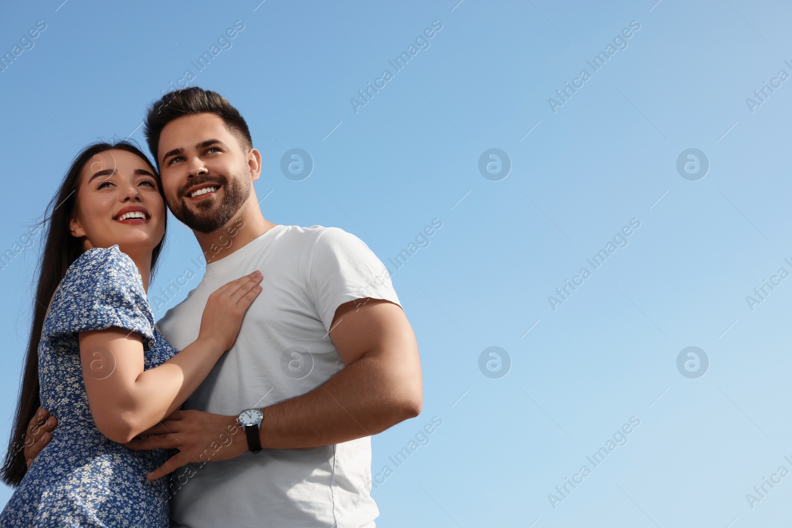 Photo of Romantic date. Beautiful couple spending time together against blue sky, low angle view with space for text