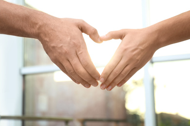 Young people forming heart with hands indoors, closeup. Happy family