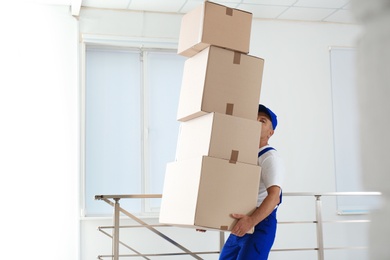 Man in uniform carrying carton boxes indoors. Posture concept