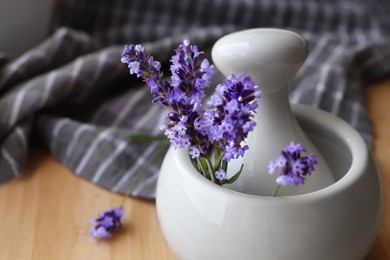 Photo of Mortar with fresh lavender flowers and pestle on table, closeup. Space for text