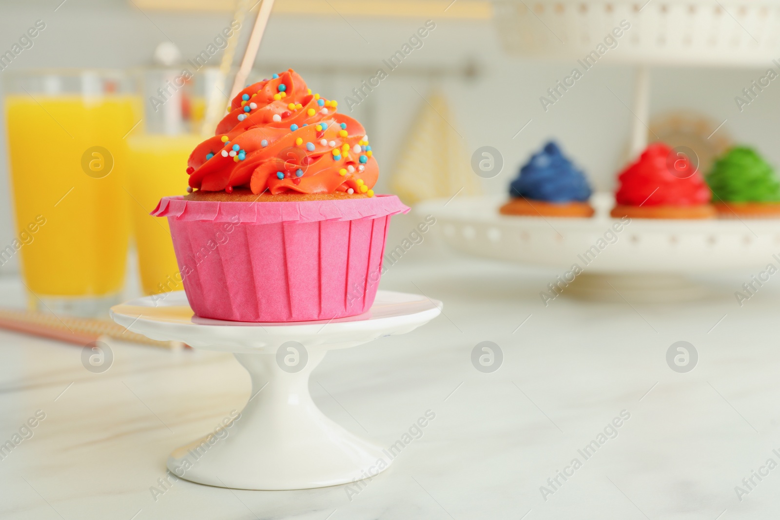 Photo of Delicious cupcake with bright cream and sprinkles on white table, space for text