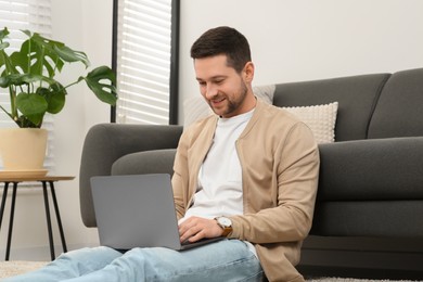 Photo of Man working with laptop on floor at home