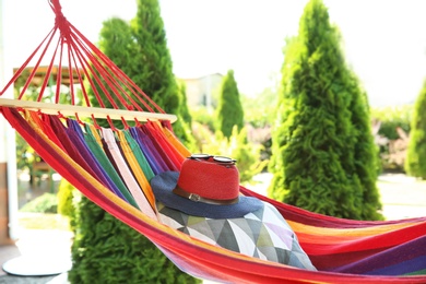 Photo of Hat, pillow and sunglasses on colorful hammock outdoors