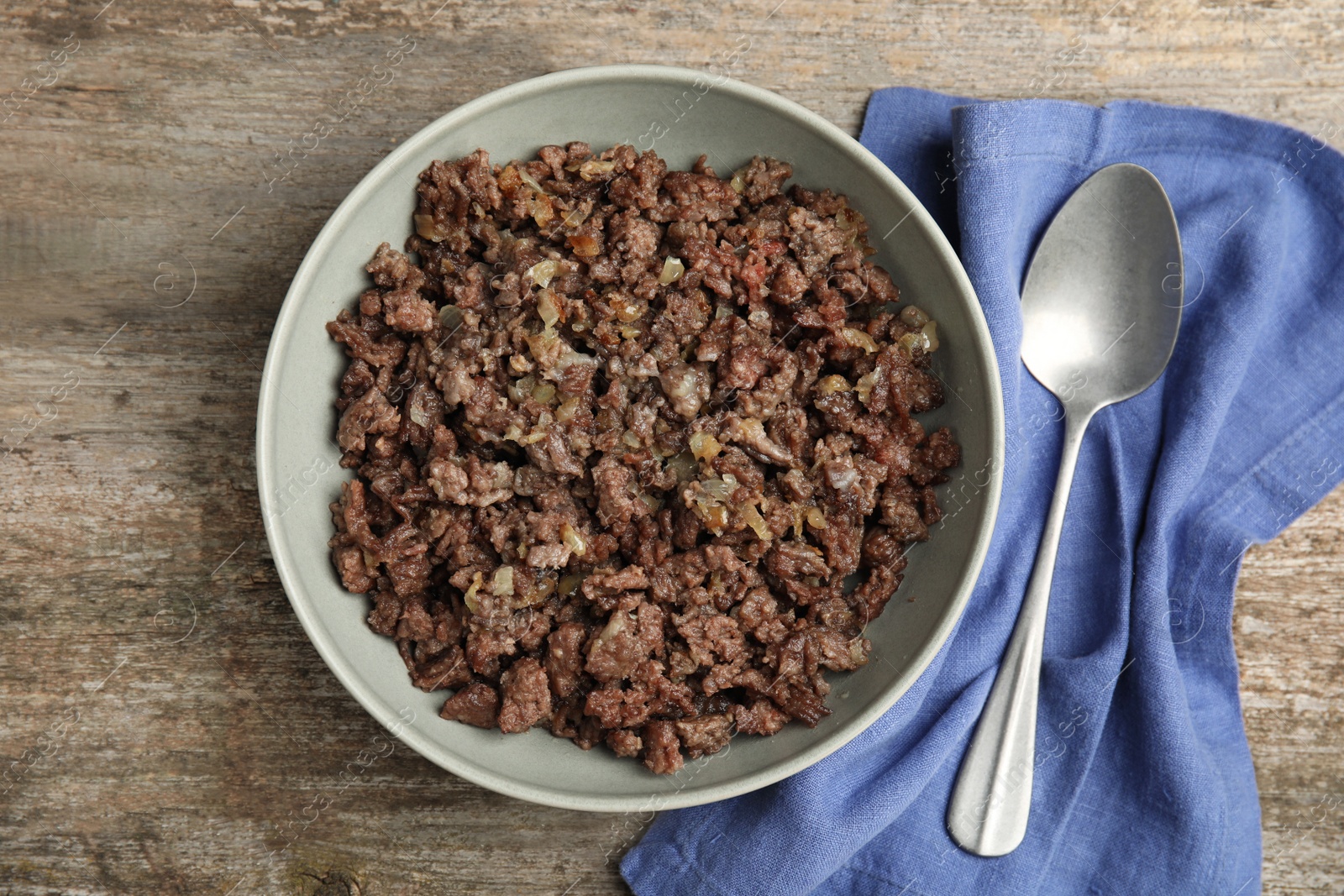 Photo of Fried minced meat, spoon and napkin on wooden table, top view