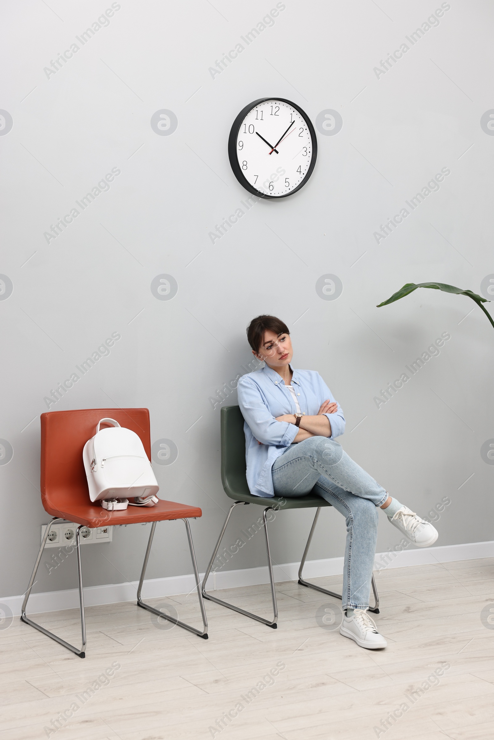 Photo of Woman sitting on chair and waiting for appointment indoors