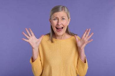 Portrait of surprised senior woman on violet background