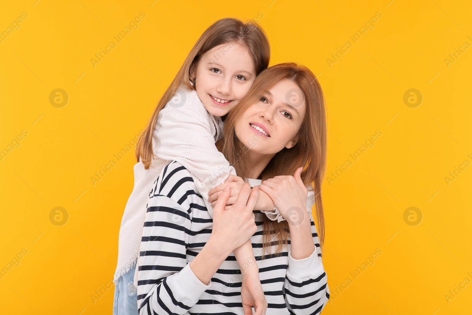Photo of Portrait of happy mother and her cute daughter on orange background