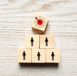 Image of Cubes with icons on wooden table, top view. Target and human illustrations