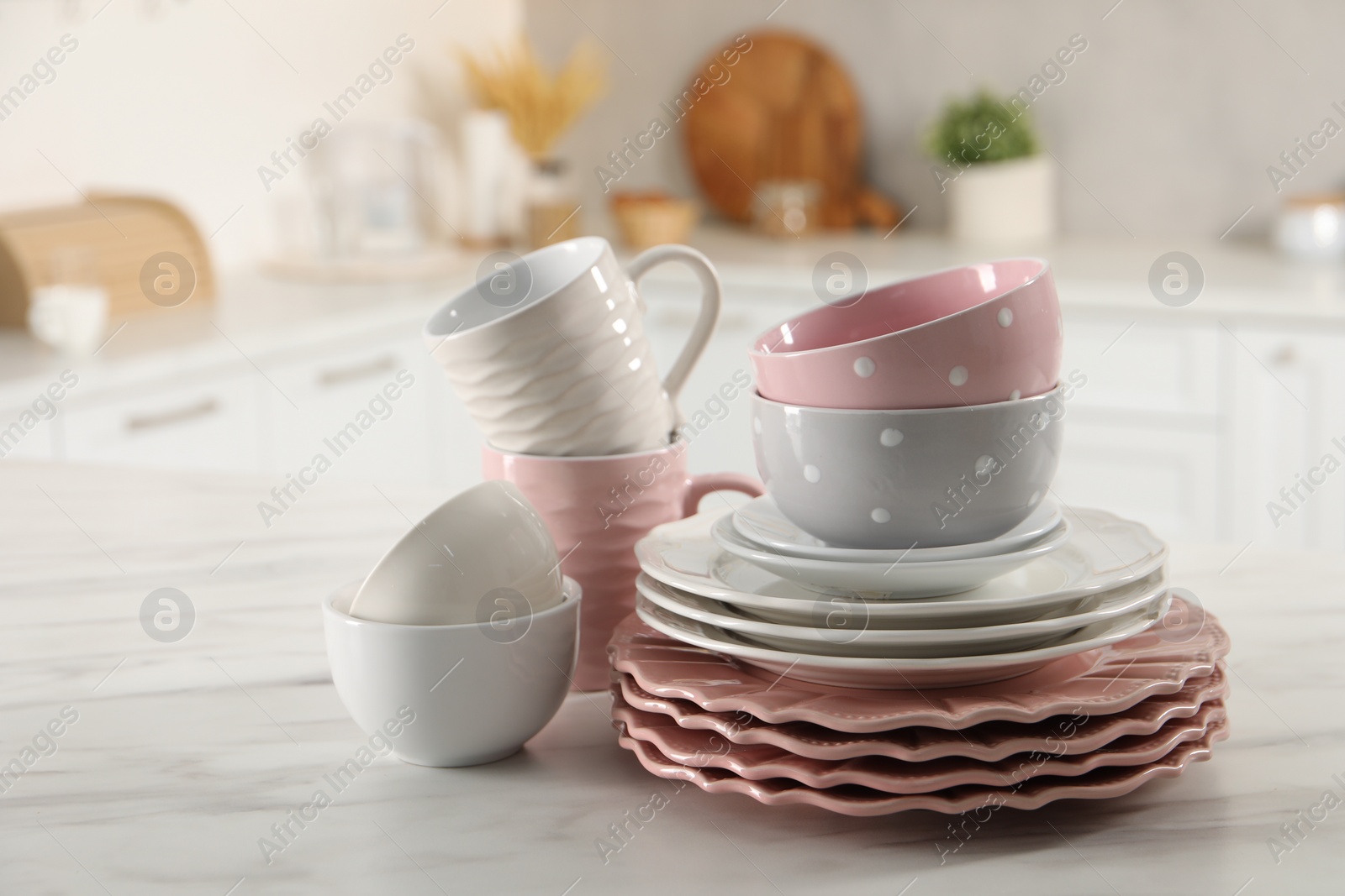 Photo of Many different clean dishware and cups on white marble table in kitchen