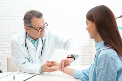 Photo of Doctor checking young woman's pulse with fingers in hospital