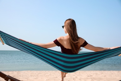 Photo of Young woman relaxing in hammock on beach