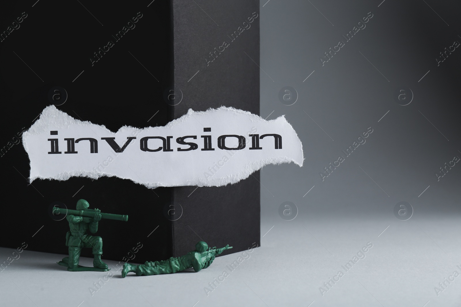 Photo of Paper with word Invasion and toy soldiers on light grey background. Space for text