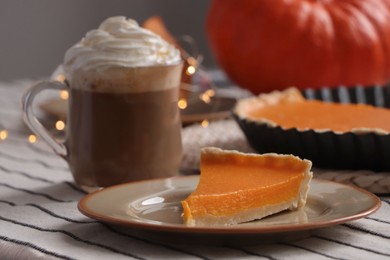 Photo of Fresh homemade pumpkin pie and cup of cocoa with whipped cream on table