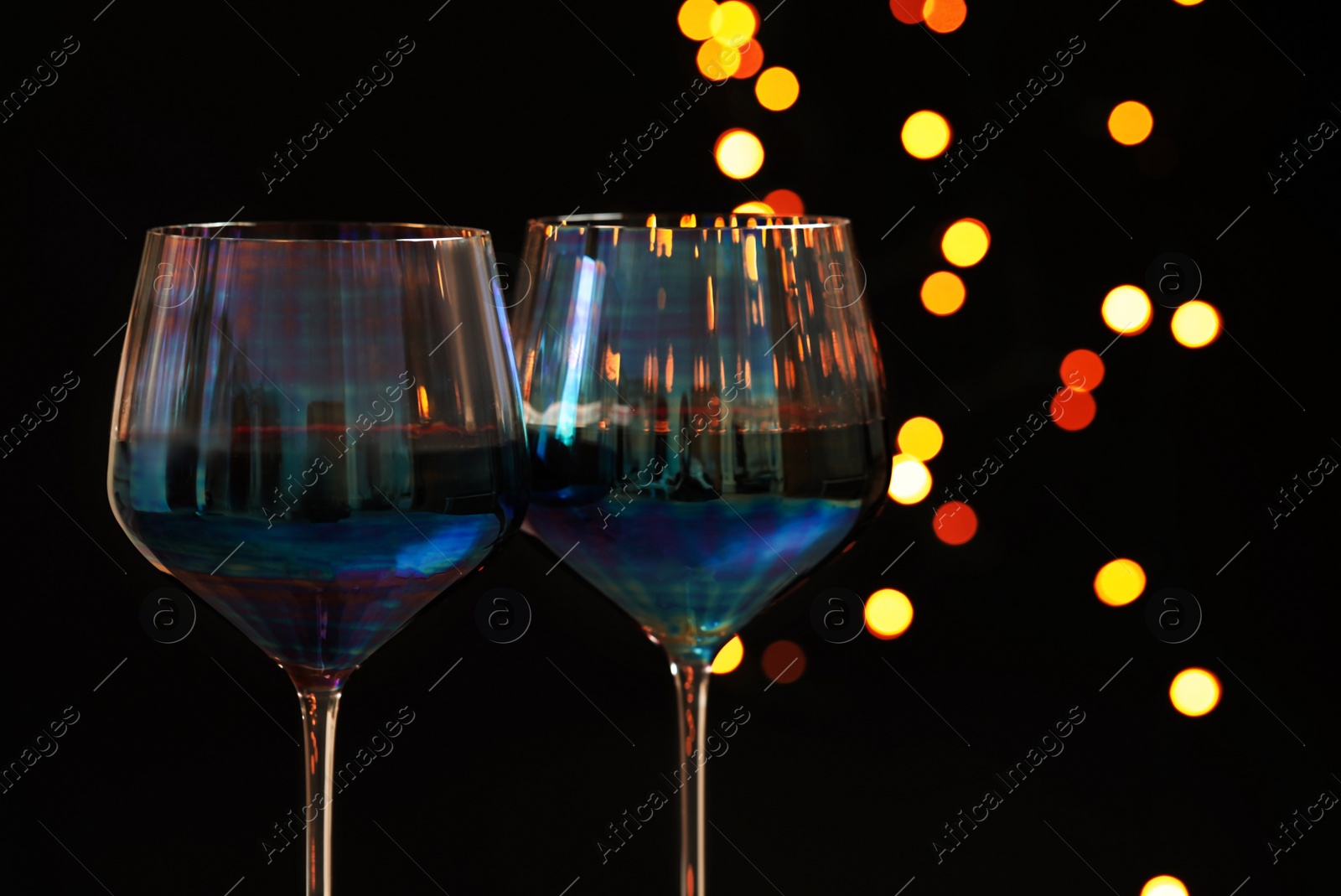 Photo of Glasses of red wine against blurred lights, closeup