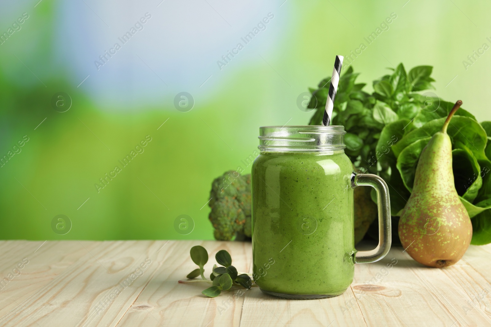 Photo of Mason jar of fresh green smoothie and ingredients on wooden table, space for text