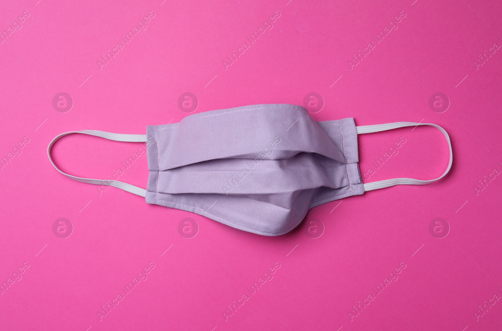 Photo of Homemade protective mask on pink background, top view. Sewing idea