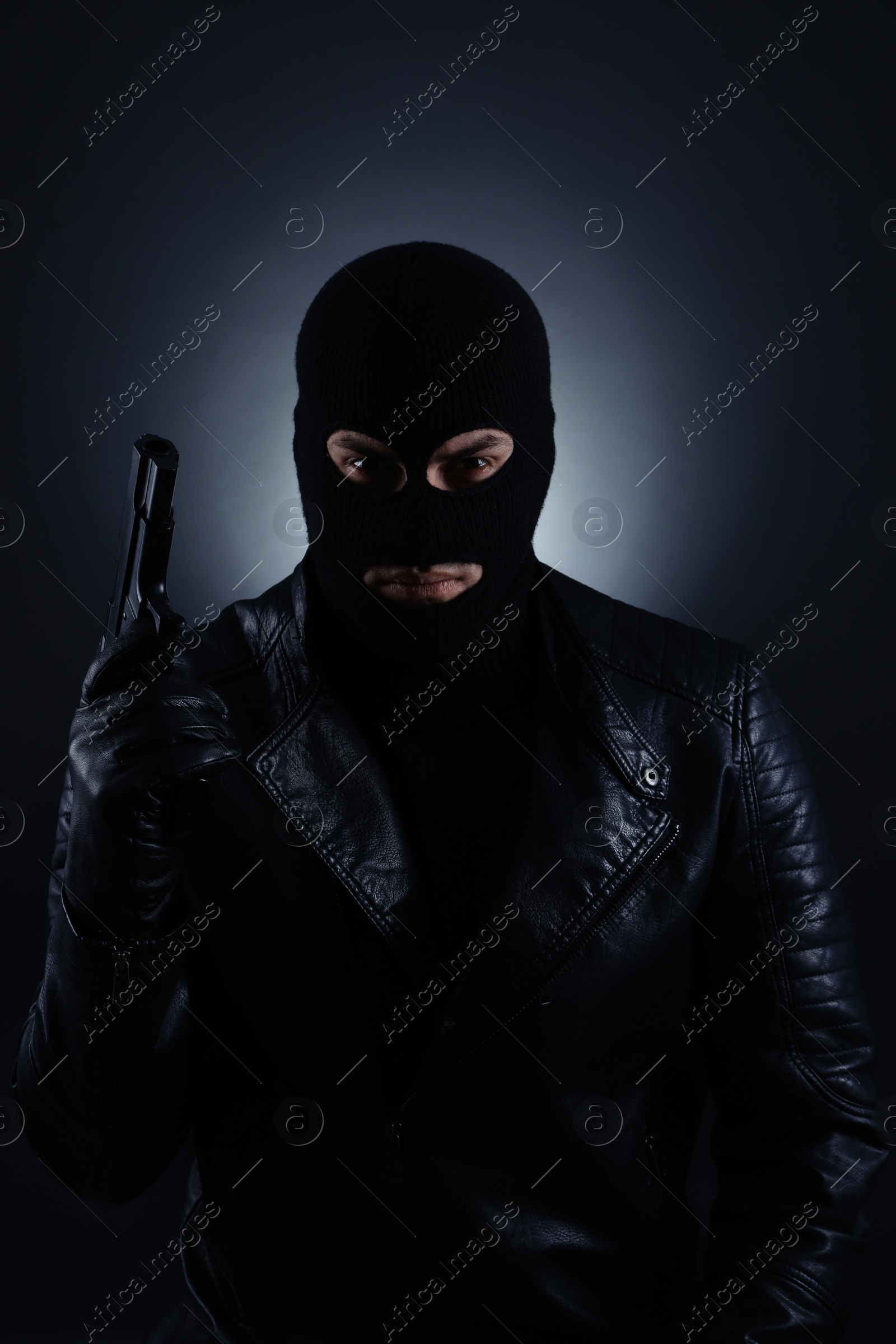 Photo of Man wearing knitted balaclava with gun on black background