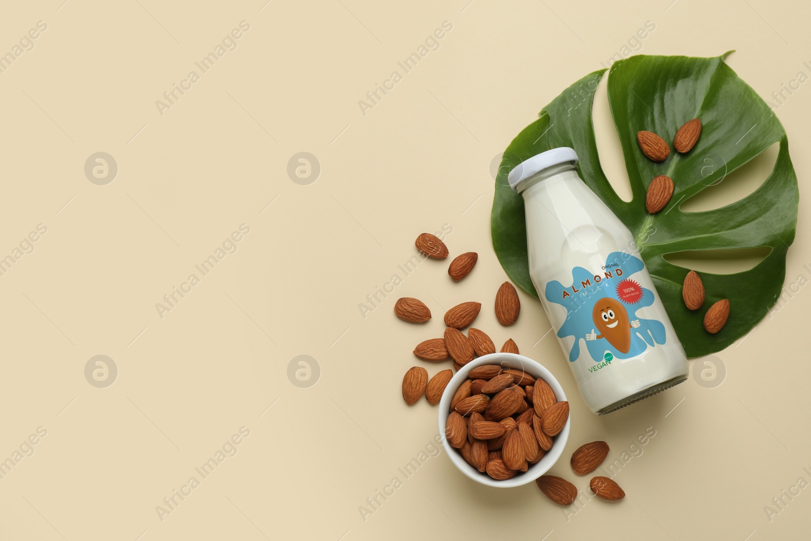 Image of Bottle of almond milk and nuts on beige background, flat lay with space for text. Vegan product