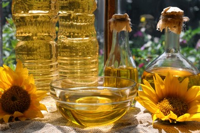 Photo of Organic sunflower oil and flowers on fabric near window, closeup