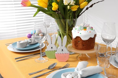Photo of Festive table setting with traditional Easter cake and vase of tulips