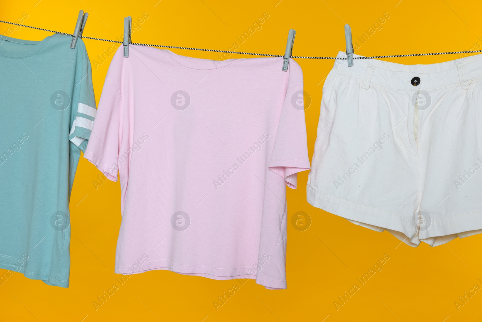 Photo of Different clothes drying on laundry line against orange background