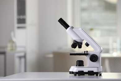 Modern medical microscope on white table in laboratory, space for text