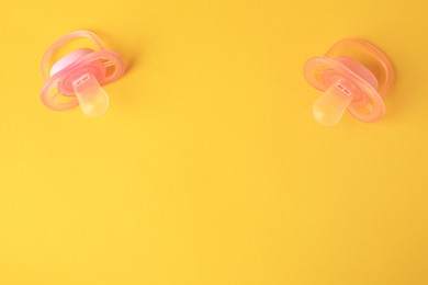 Photo of New baby pacifiers on orange background, flat lay. Space for text