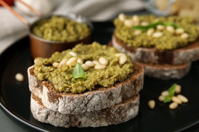 Photo of Tasty bruschettas with pesto sauce and nuts on plate, closeup