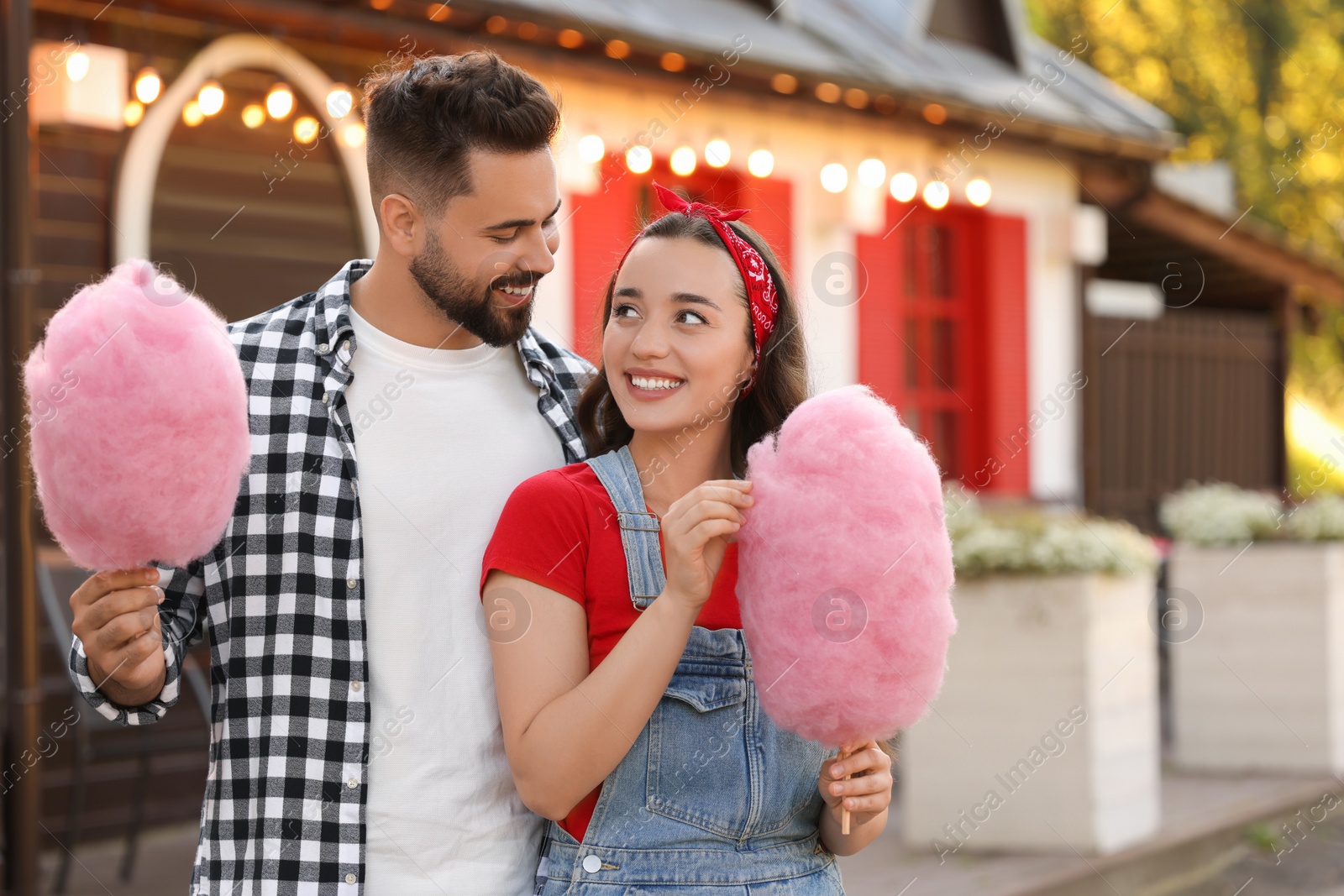 Photo of Happy couple with cotton candies spending time together outdoors