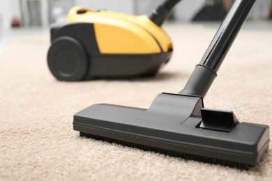 Photo of Removing dirt from carpet with vacuum cleaner indoors, closeup