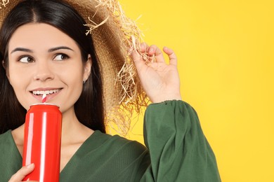 Beautiful happy woman drinking from red beverage can on yellow background. Space for text