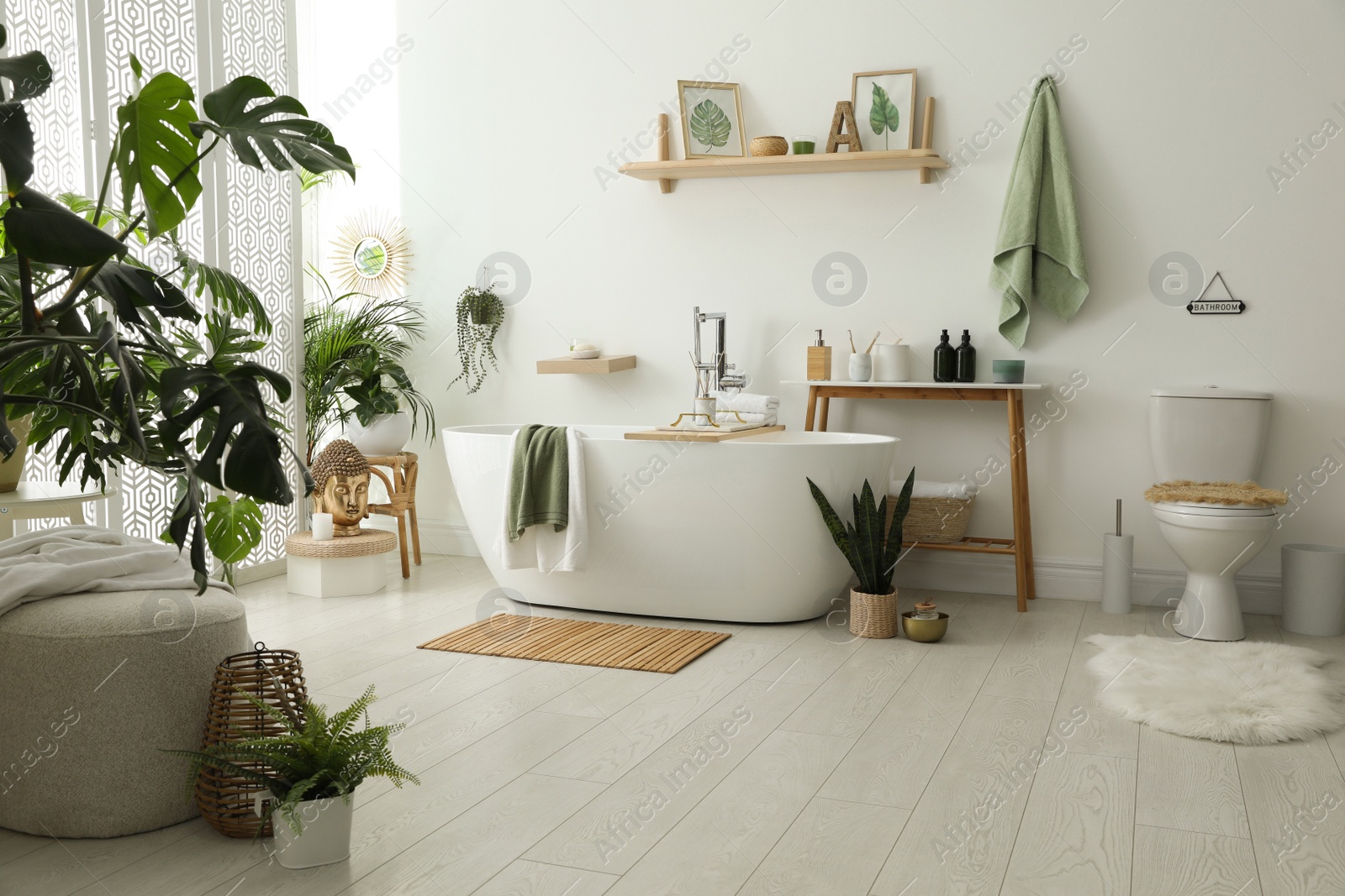 Photo of Stylish bathroom interior with modern tub, houseplants and beautiful decor. Home design