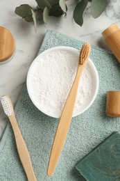 Flat lay composition with tooth powder and brushes on white marble table