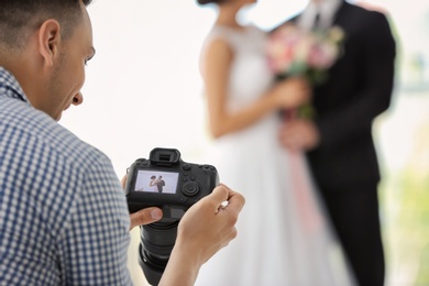 Professional photographer with camera and wedding couple in studio