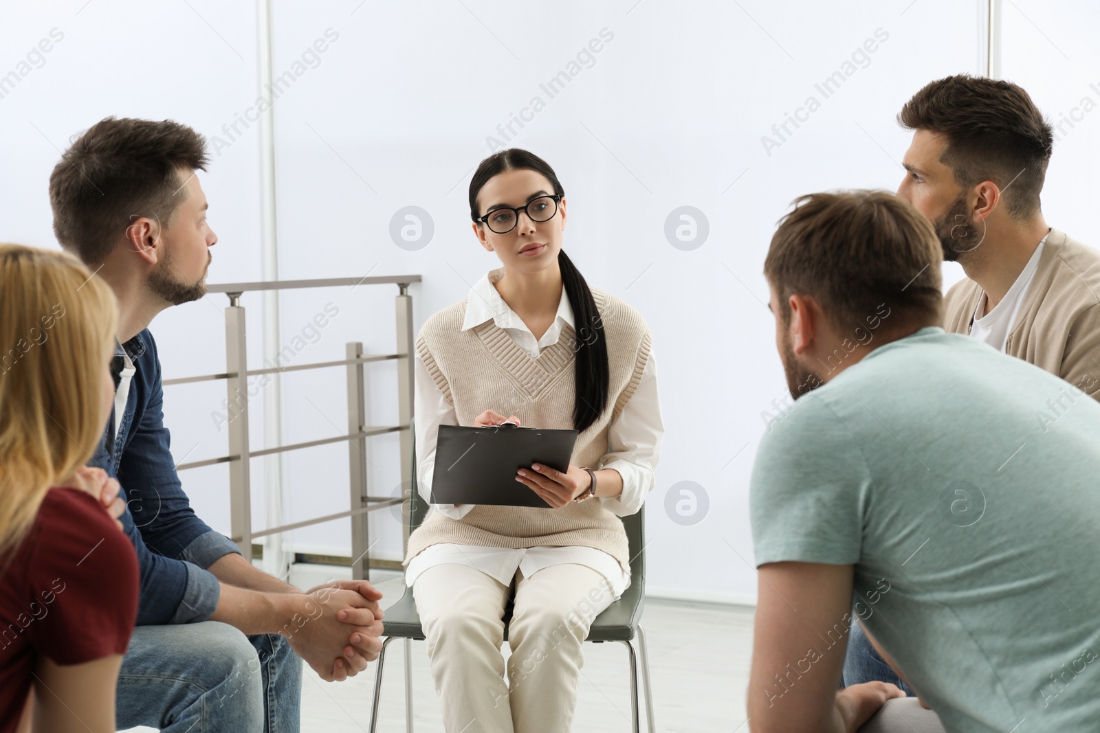 Photo of Psychotherapist working with group of drug addicted people at therapy session indoors