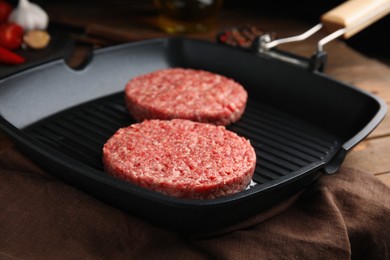 Photo of Raw hamburger patties with oil on grill pan, closeup