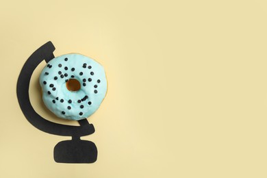 Photo of Globe made of tasty doughnut and drawing on beige background, top view. Space for text