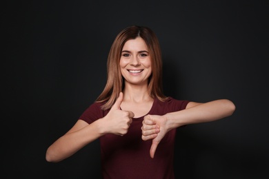 Photo of Woman showing THUMB UP and DOWN gesture in sign language on black background