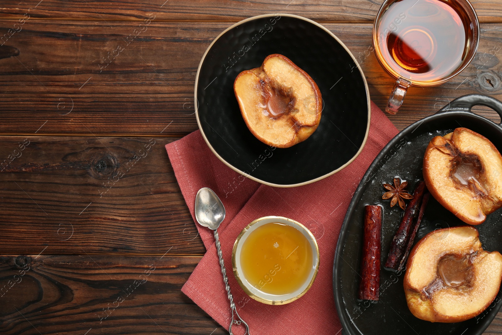 Photo of Tasty baked quinces served with honey and tea on wooden table, flat lay. Space for text