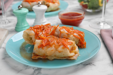 Photo of Delicious cabbage rolls served on white marble table, closeup